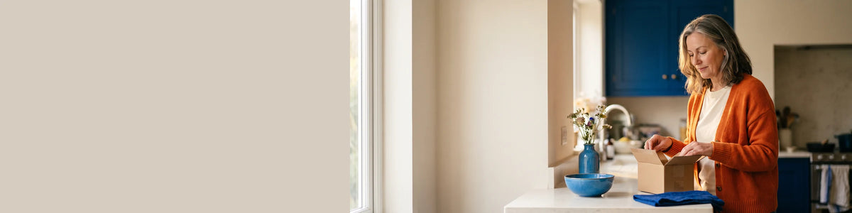 Woman opening a delivery in her kitchen, 4:1 strip